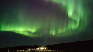 A house with a lighted exterior at night, surrounded by a grassy landscape. - Brekkukot Cottage  (Blönduós)