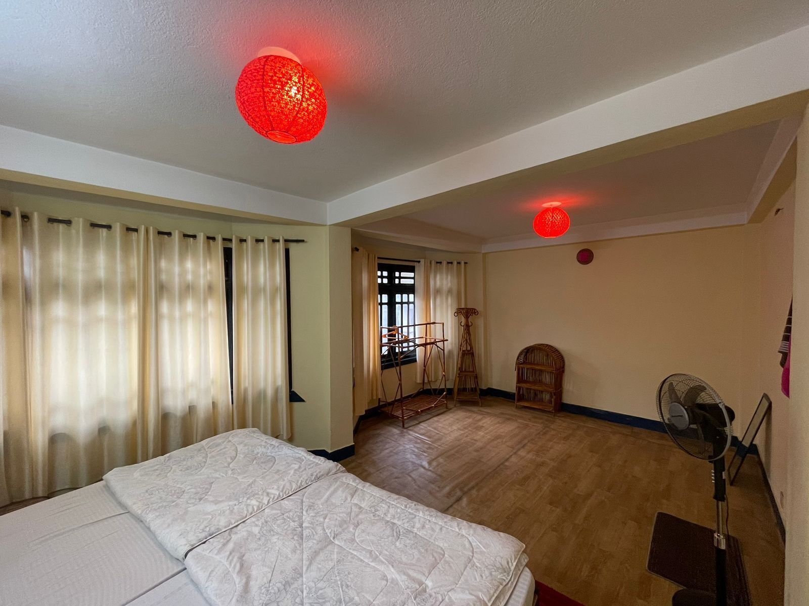 A hotel room with two beds, a standing fan, and a red decorative light on the ceiling.