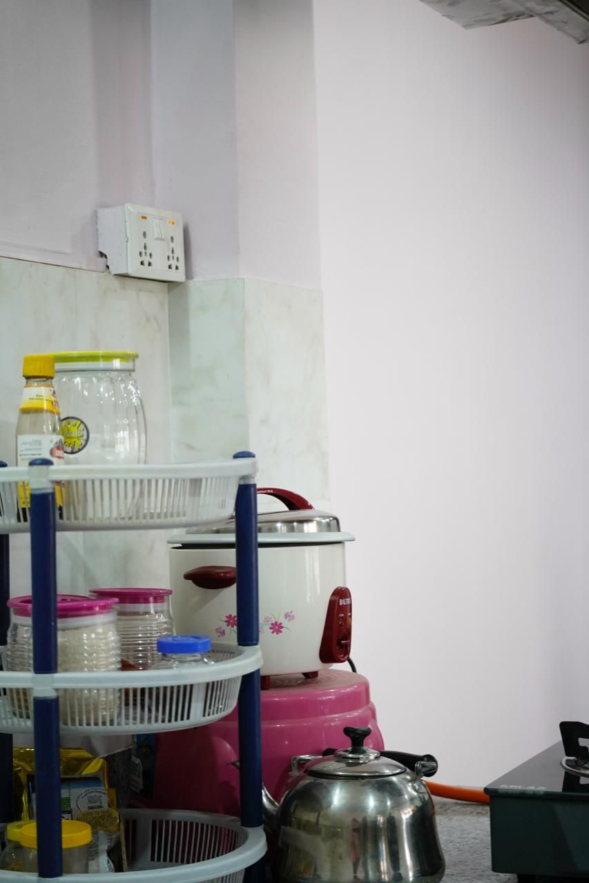 Una cocina con un hervidor, un electrodoméstico rosa y un enchufe blanco en la pared.