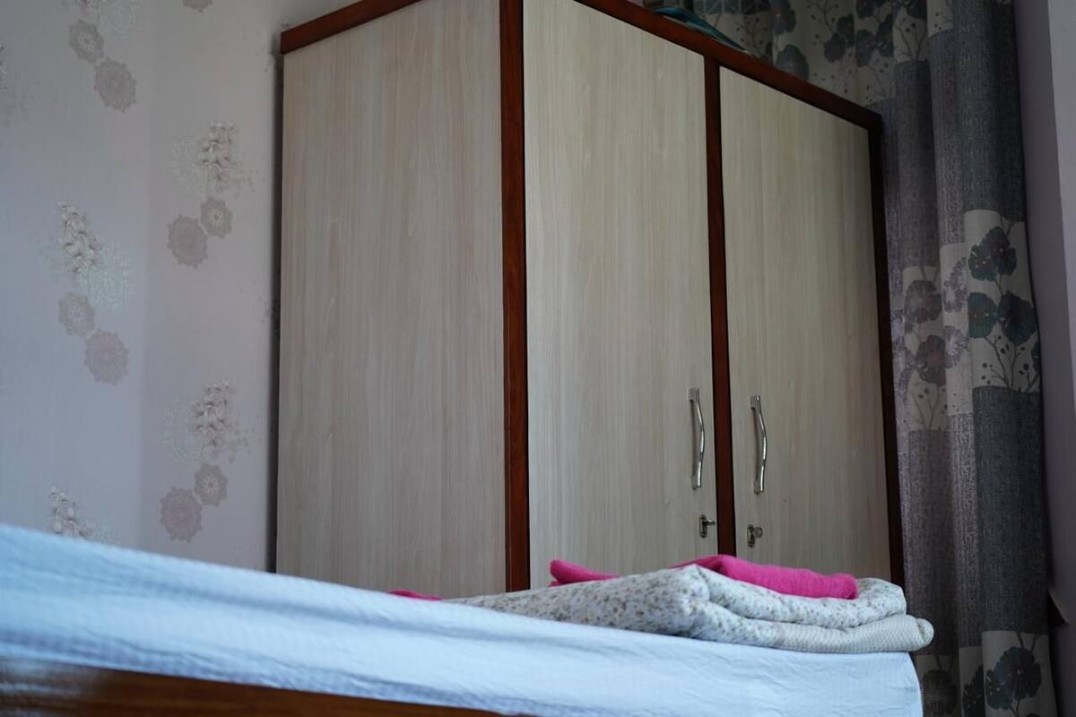 A bedroom with a bed, a wardrobe, and floral wallpaper.