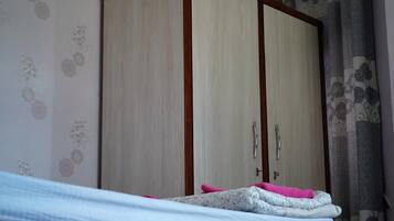 A bedroom with a bed, a wardrobe, and floral wallpaper.