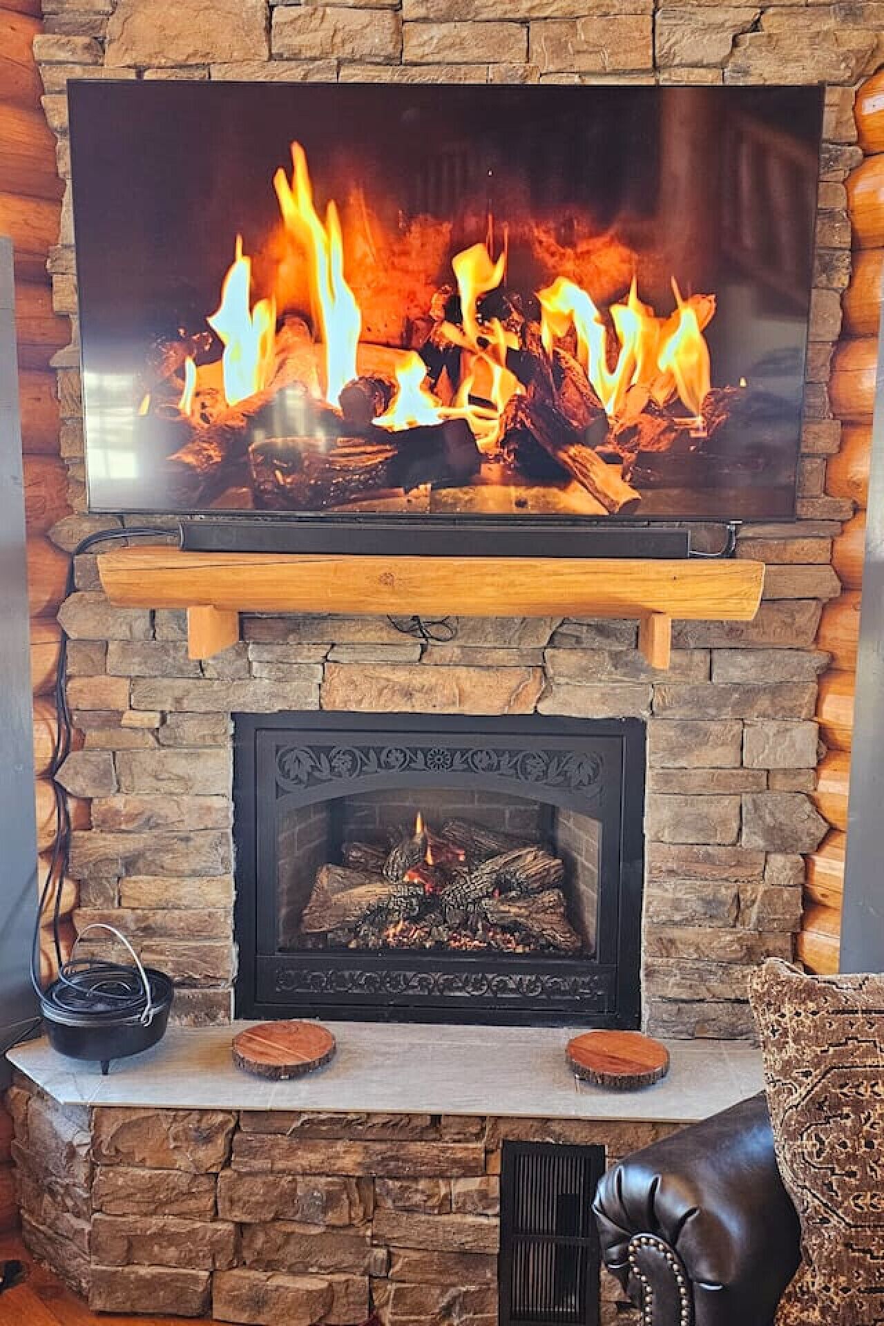 Ein Kamin mit einem darüber befindlichen Fernseher, der ein Feuer zeigt.