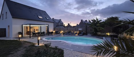 A swimming pool with lounge chairs and a covered patio area.