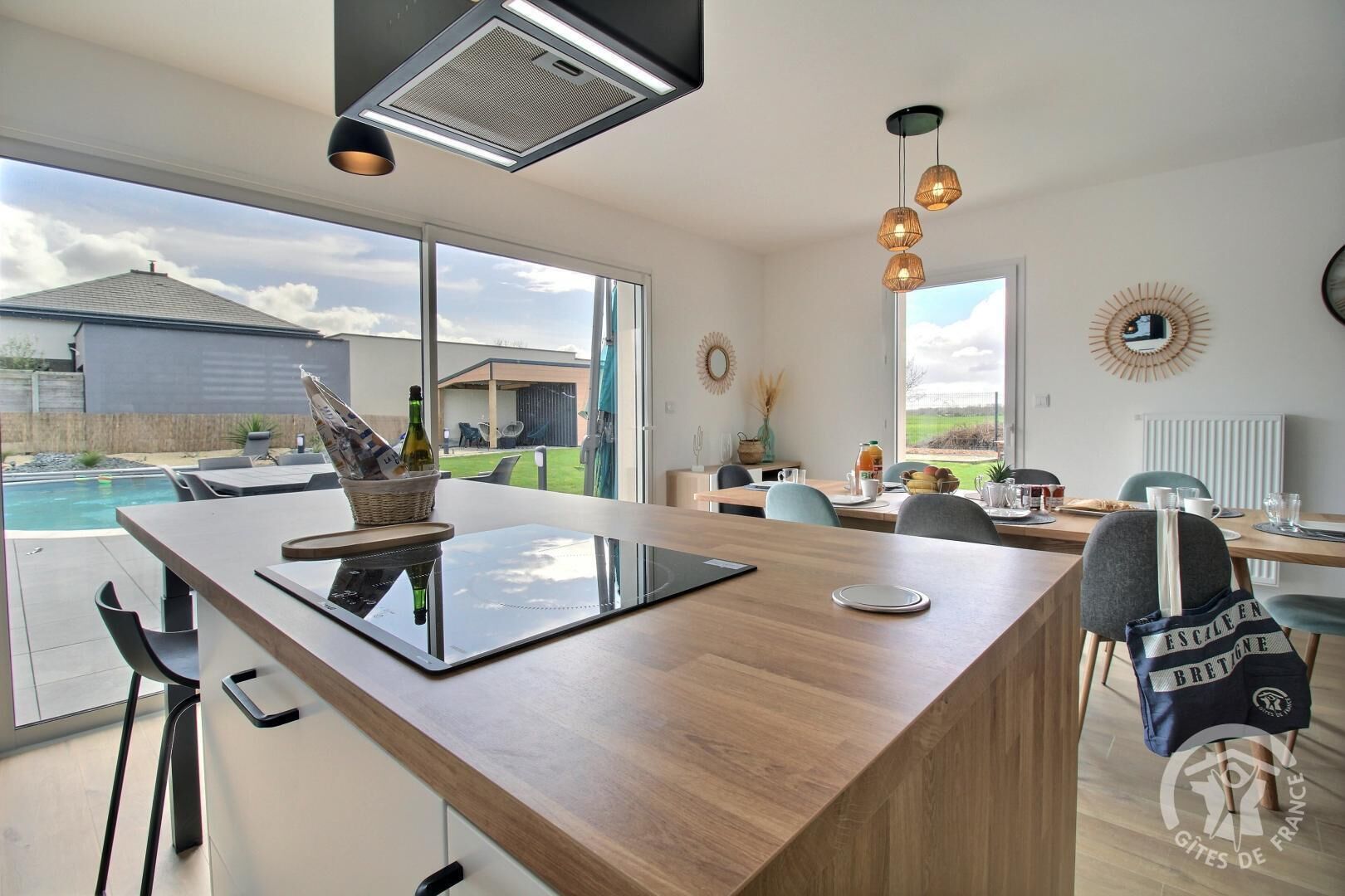 A modern kitchen with a large island, a dining area, and a view of a swimming pool.