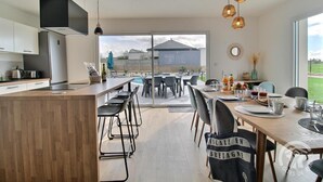 Eine moderne Küche mit einer großen Kochinsel, einem Essbereich mit Stühlen und Blick auf den Garten.