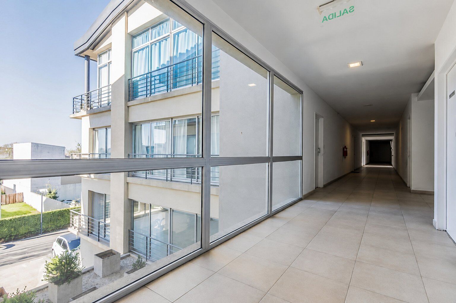 Un bâtiment moderne doté de grandes fenêtres, d’un balcon couvert et d’un sol carrelé.