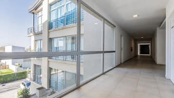 A modern building with large windows, a covered balcony, and a tiled floor.