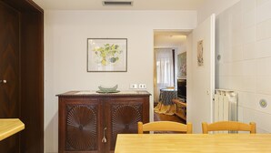 A dining area with a wooden table and chairs, a cabinet with a decorative top, and a framed artwork on the wall. - Fresco-Rialto (Venice)