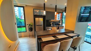 A modern kitchen with a central island, pendant lighting, and a view of the outside. - Republica del Salvador Coliving Ecuador (Quito)
