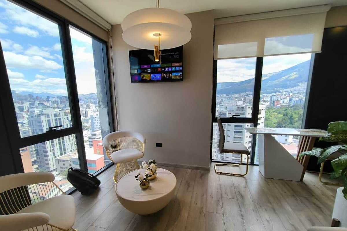 A modern living room with large windows, a flat-screen TV, and a city view.