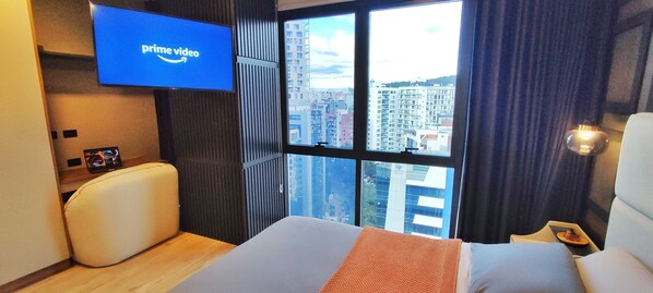 A hotel room with a large window, a bed, a flat-screen TV displaying 'prime video', and a city view. - Republica del Salvador Coliving Ecuador (Quito)