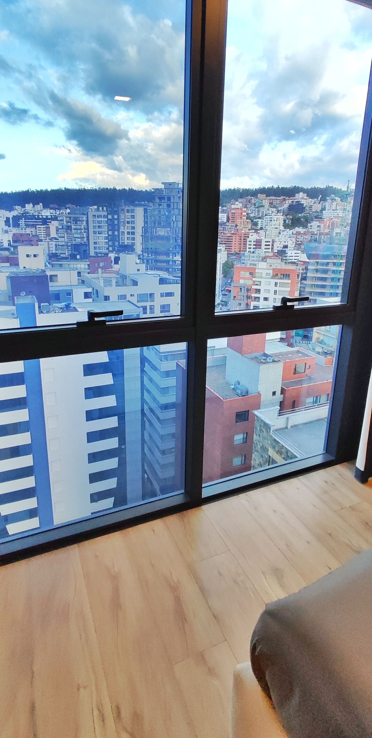A room with large windows offering a view of a cityscape with various buildings.