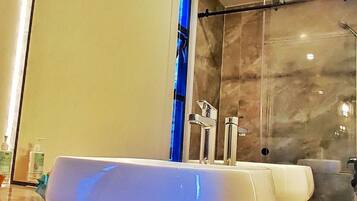 A bathroom with a white sink, a large mirror, and a hanging light fixture.
