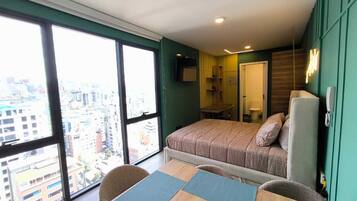 Een moderne slaapkamer met een groot raam, een bed, een bureau en een stoel.