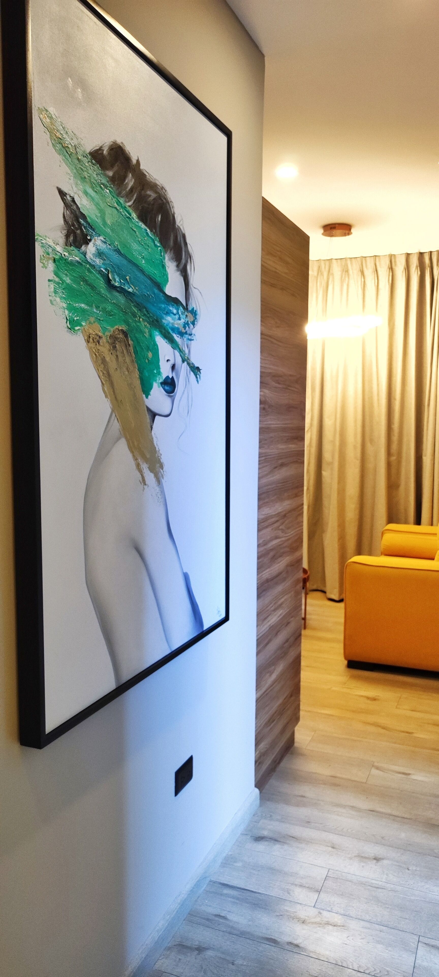 A modern living room with a large abstract painting on the wall, a wooden accent wall, a yellow sofa, and a wooden floor.
