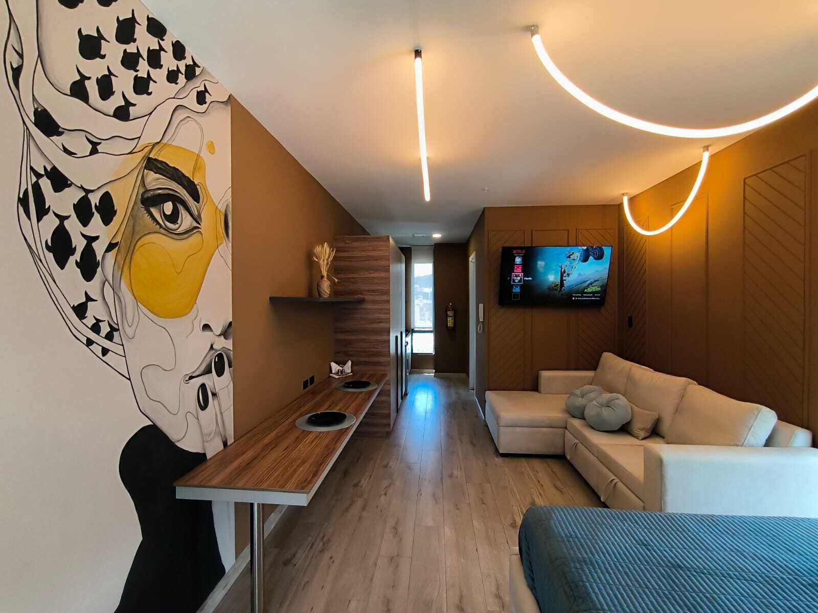Uma sala de estar moderna com televisão de tela plana, mesa de jantar de madeira e um sofá.