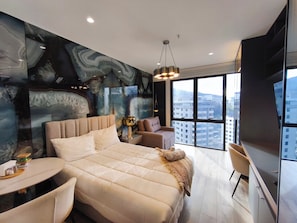 Un dormitorio moderno con una cama grande, un rincón de descanso y vistas a la ciudad.