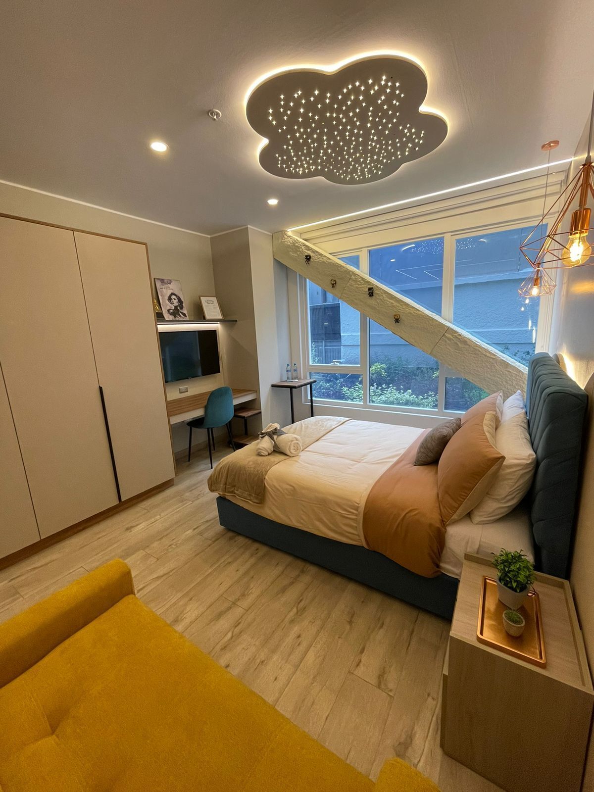 A modern bedroom with a bed, a desk, and a window.