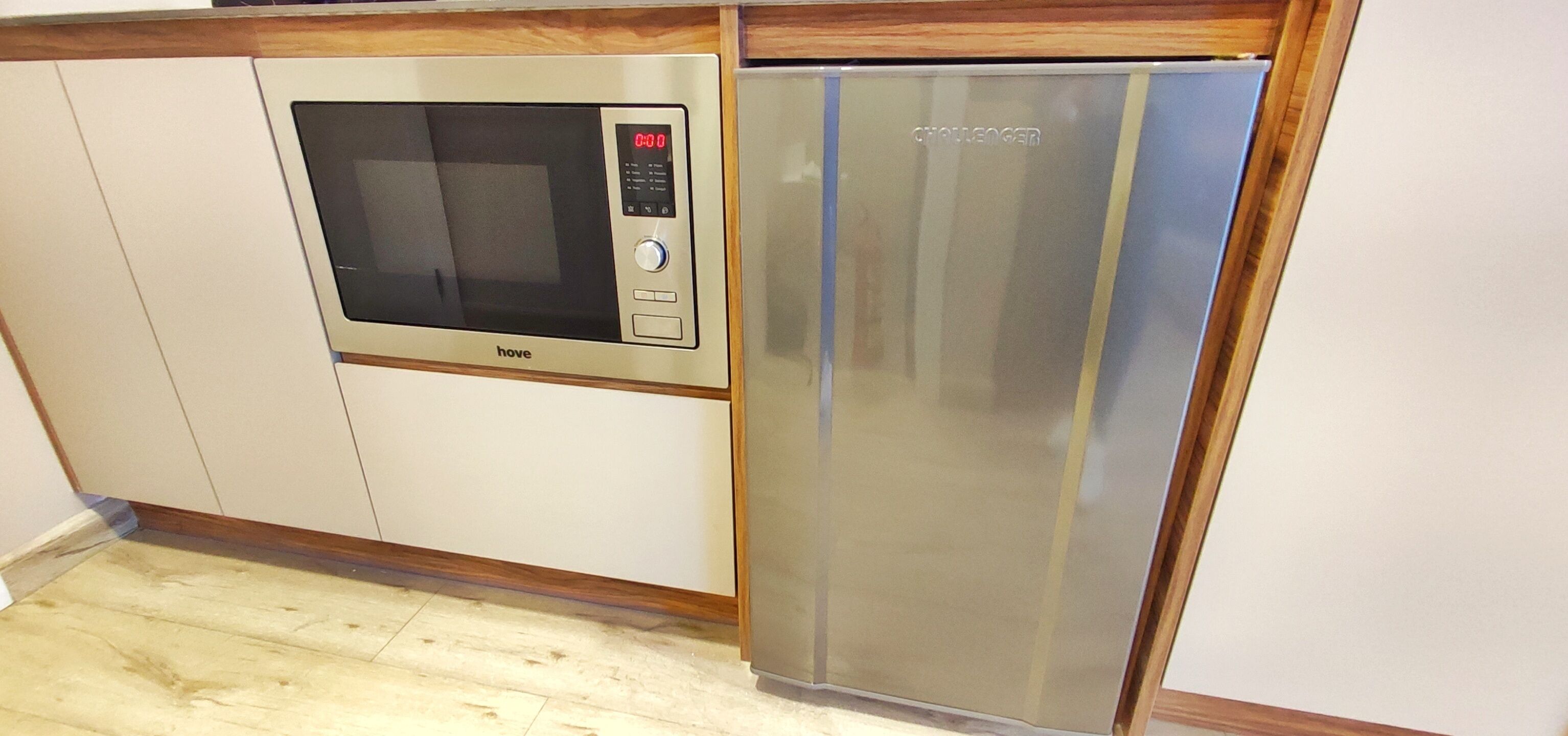 A kitchenette with a microwave and a stainless steel refrigerator.