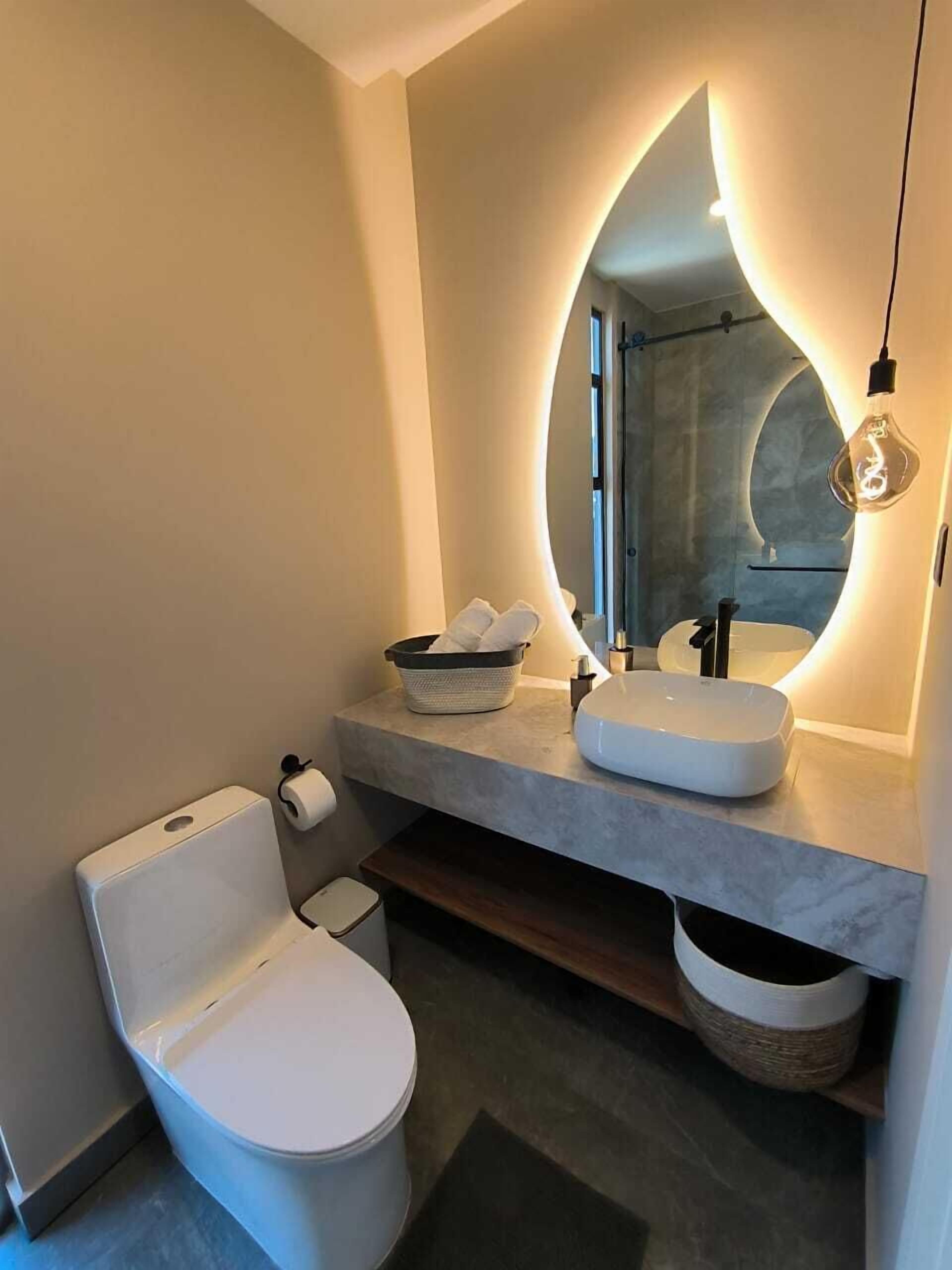 A modern bathroom with a white toilet, a sink with a mirror, and a light fixture.