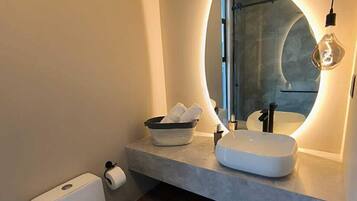 A modern bathroom with a white toilet, a sink with a mirror, and a light fixture.
