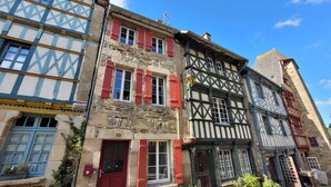 A traditional half-timbered building with red shutters and a stone facade.