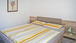 Un lit double avec une literie à rayures, une table de chevet, une lampe et un tableau encadré au mur.