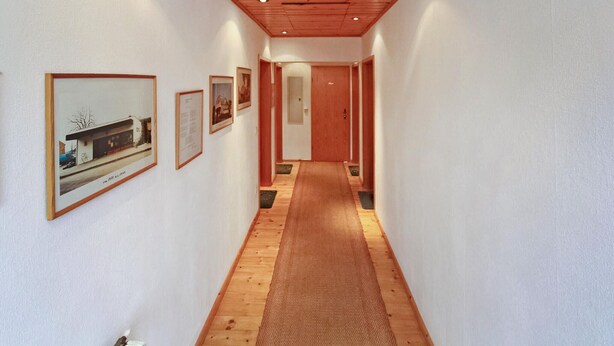 Un corridoio con quadri appesi alle pareti, pavimento in legno e soffitto di legno.