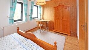 Una camera da letto con un letto di legno, una scrivania e un armadio.