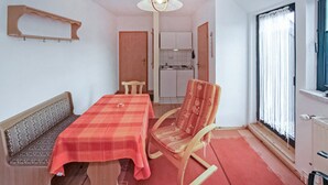 Una stanza compatta con un tavolo da pranzo, una poltrona a dondolo, una panca e una finestra con tende.