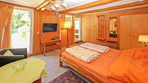 A wooden room with a bed, a desk, a TV, and a window. - Ferienhaus Rheinsberg (Rheinsberg OT Zechline)