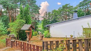 Una cabaña rústica rodeada de un bosque denso, con una cerca de madera y casas para pájaros.