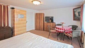 Hotelkamer met een bed, televisie, eettafel met stoelen, kledingkast en een schilderij aan de muur.
