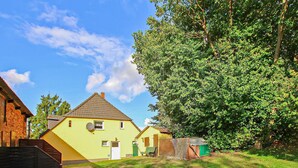 Een geel huis met een schuin dak, een klein terras en een groene deur.