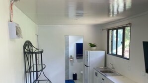 Una cocina compacta con armarios blancos, un lavamanos integrado y una ventana.
