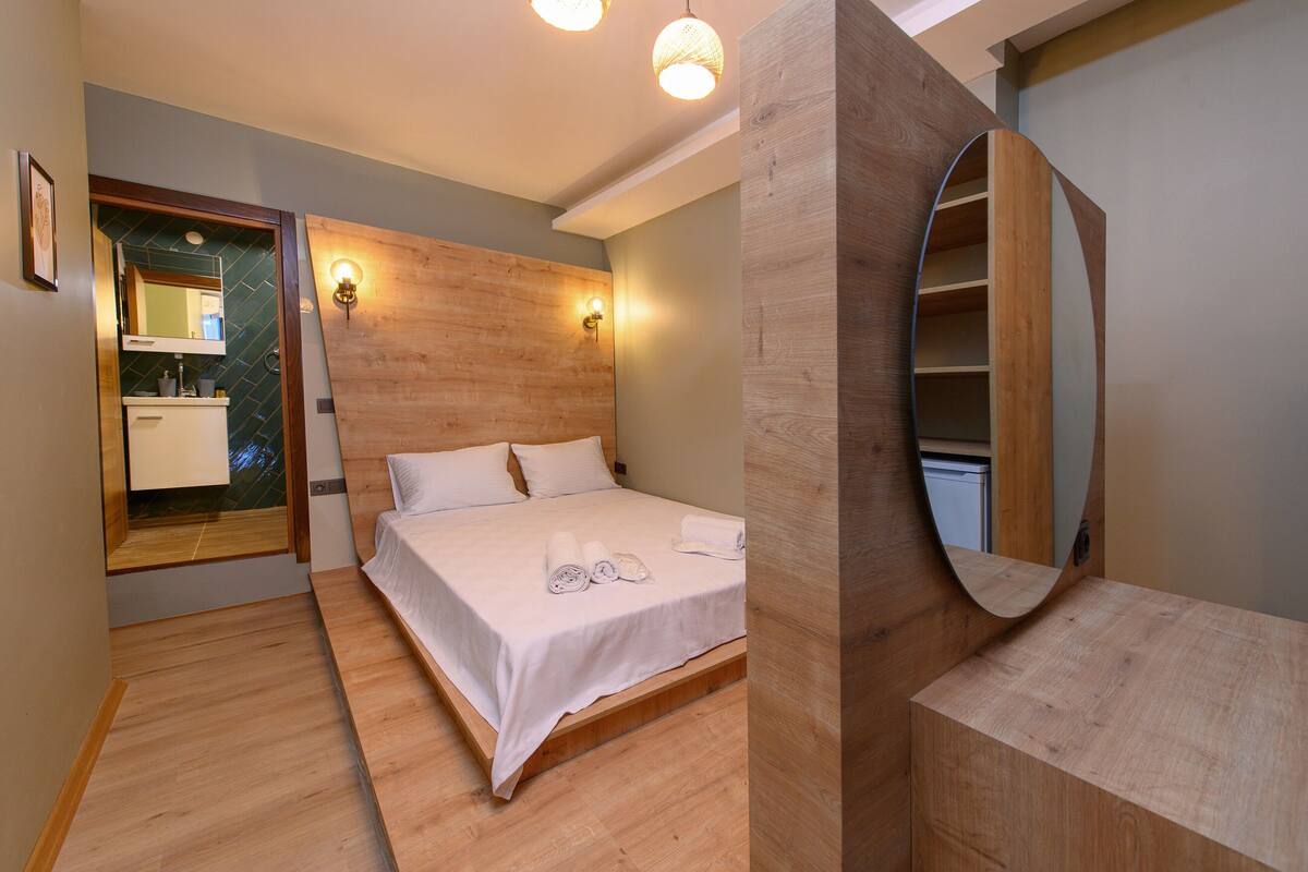 Un dormitorio moderno con cabecera de madera, un espejo grande y un estante de madera empotrado.