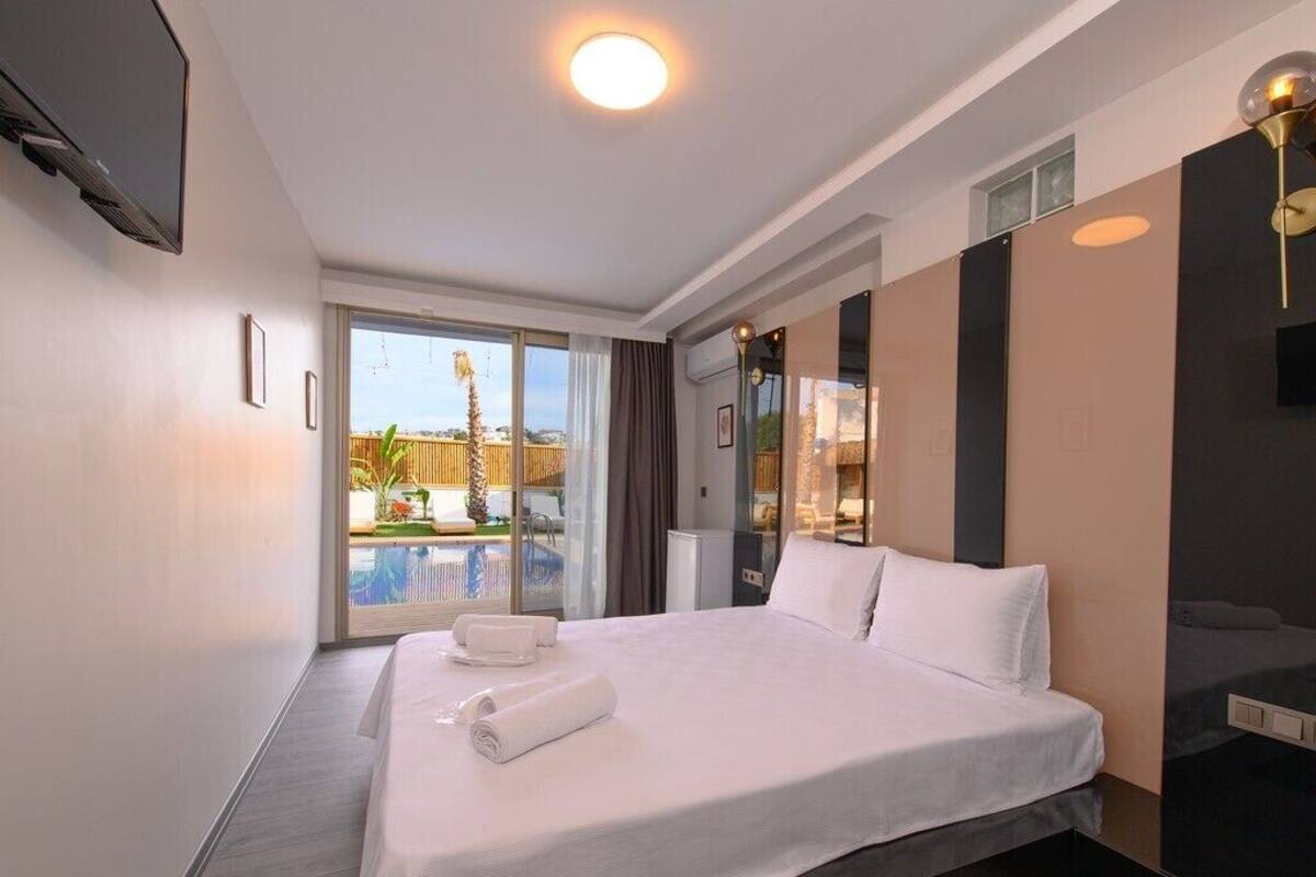 Habitación de hotel con una cama grande, televisión, balcón con piscina y diseño moderno.
