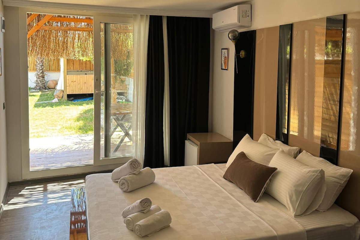 Una habitación de hotel con una cama grande, una mesita de noche y vistas al exterior.