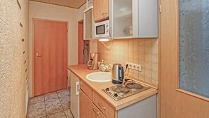 Cocina compacta con microondas, hervidor y estufa.