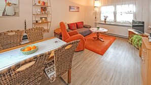 Una sala acogedora con comedor, sofá, televisión y estantería.