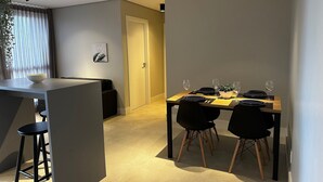A modern dining area with a long table, black chairs, and a bowl on the table. - PARK SUL - Edifício Essence (Guará)