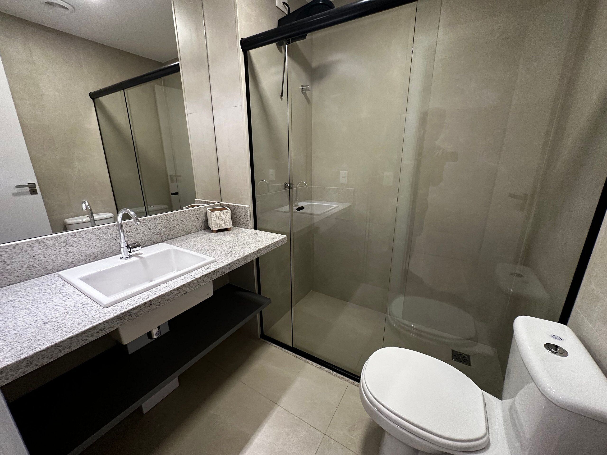 Ein modernes Badezimmer mit einer einteiligen Duschkabine, einem weißen Waschbecken und einer Toilette.