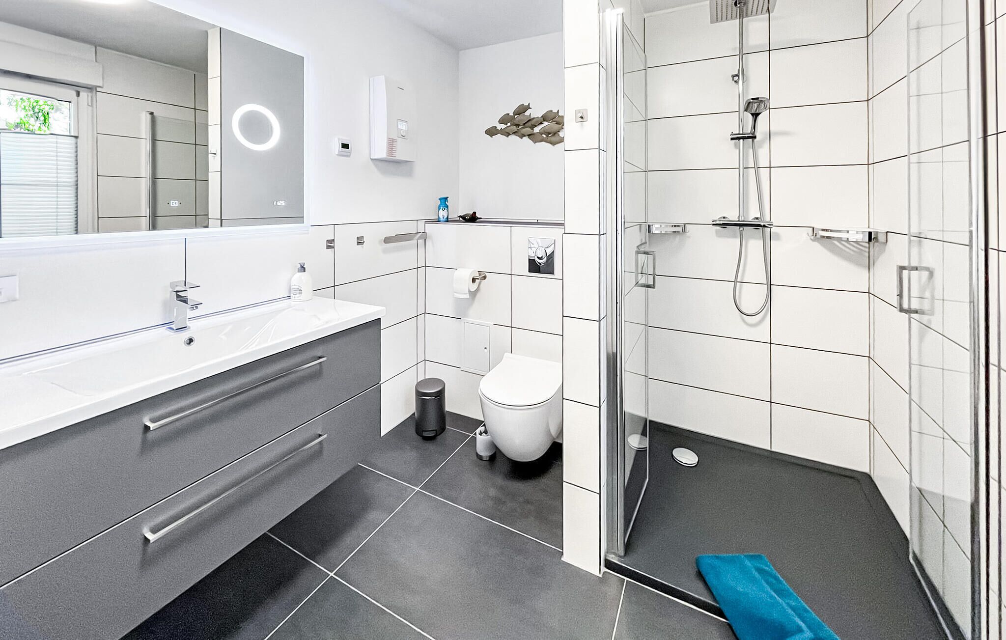 Ein modernes Badezimmer mit großem Spiegel, Toilette, Dusche und Waschbecken.