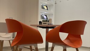Un interior moderno con dos sillones naranjas, una mesita y un estante de pared con cuadros enmarcados.