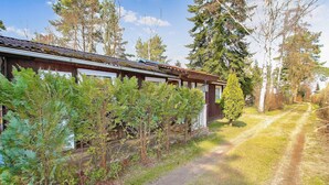 Een rustieke houten chalet, met een grindpad er naartoe, omgeven door weelderige begroeiing.