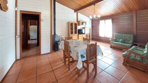 A cozy cabin interior with a dining area, a living room with a sofa, and a kitchen area.