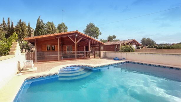 A swimming pool with a wooden deck and a covered area.