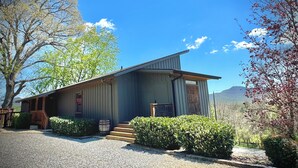 A rustic cabin with a wooden exterior, a front porch, and a gravel driveway.