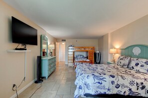 Une chambre à coucher comprenant un lit, une télévision, une commode, un miroir et un lit superposé.