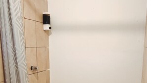 Un baño con ducha, inodoro y toallero.